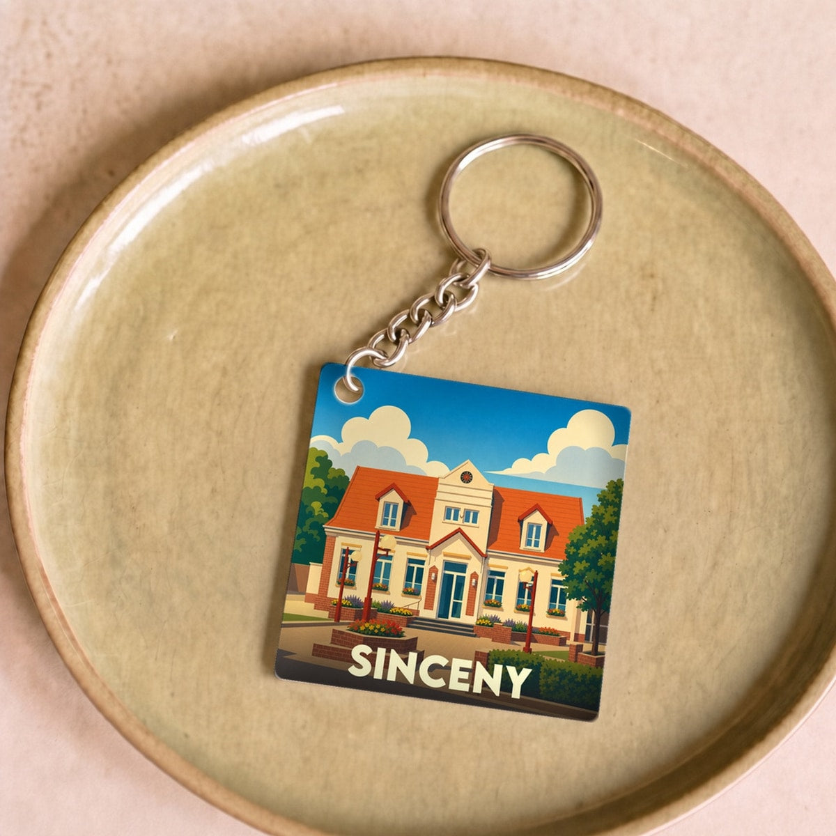 Porte-clés souvenir de la ville de Sinceny avec une illustration stylisée de sa mairie.