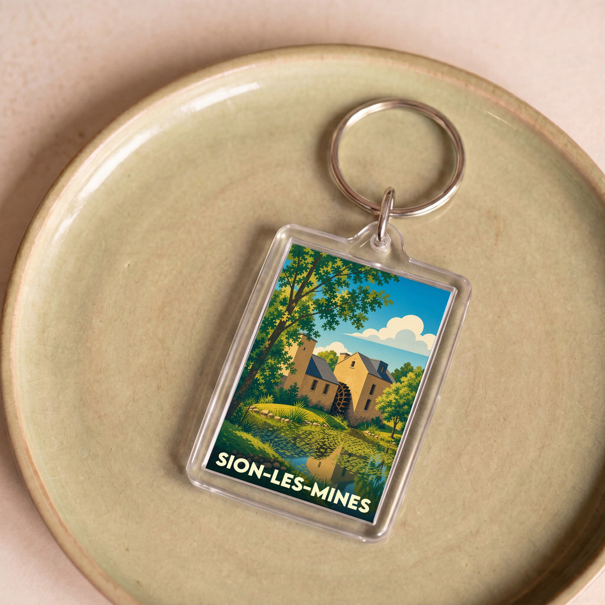 Porte-clés souvenir de la ville de Sion-les-Mines avec une illustration stylisée d'un moulin à eau.