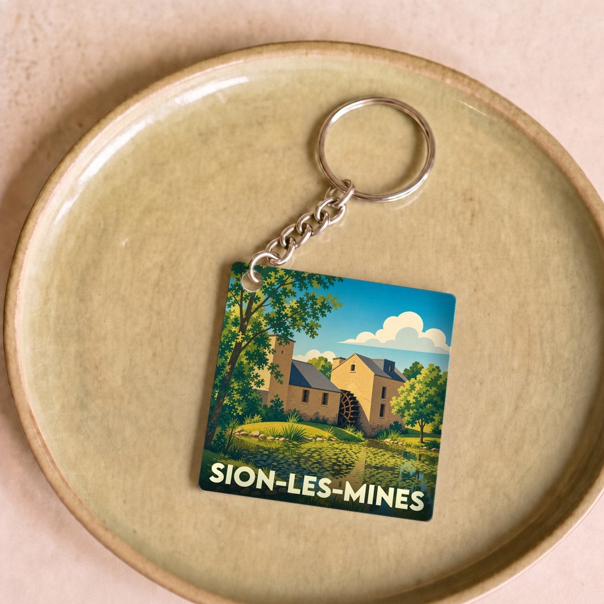 Porte-clés souvenir de la ville de Sion-les-Mines avec une illustration stylisée d'un moulin à eau.