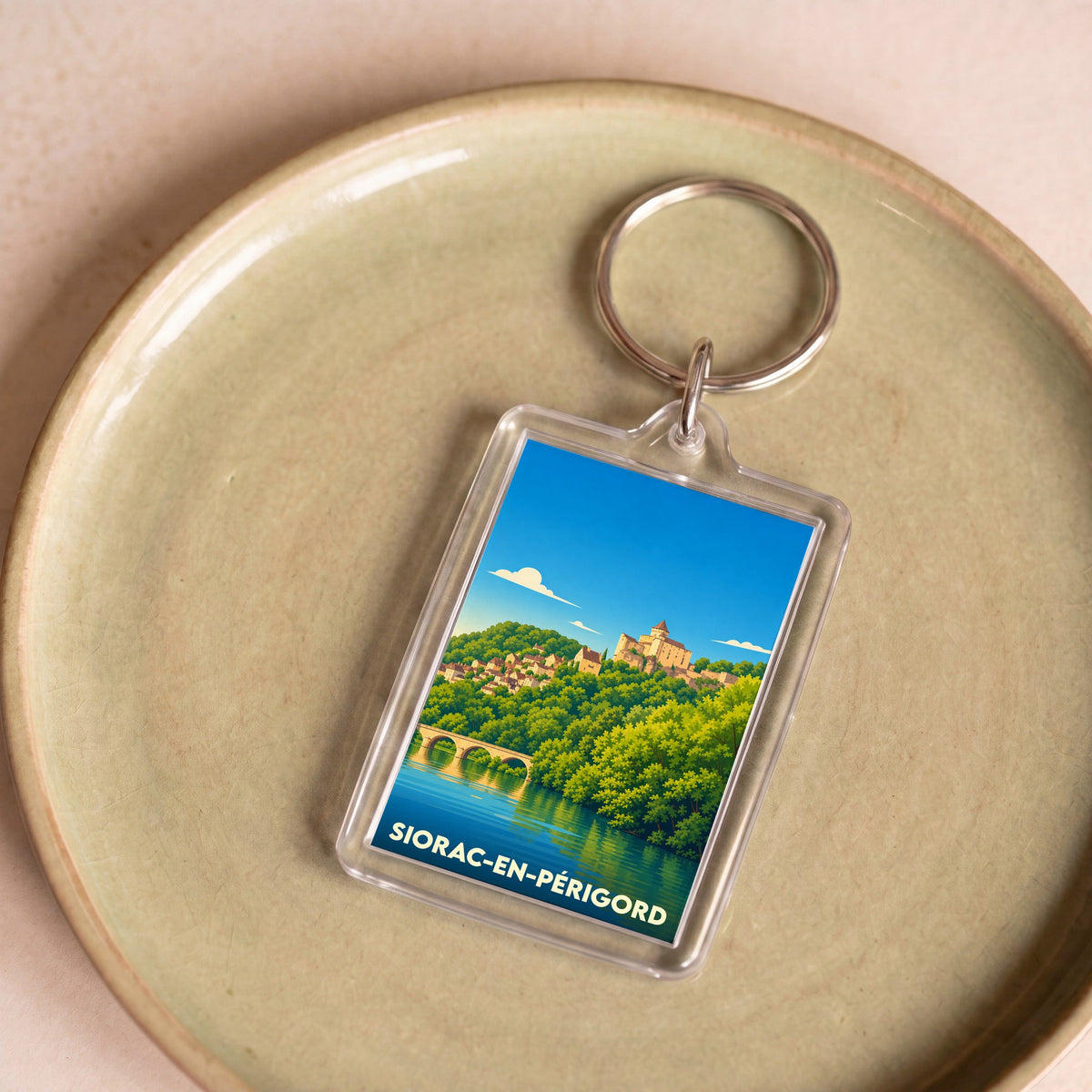 Porte-clés souvenir de Siorac-en-Périgord avec une illustration stylisée du village.