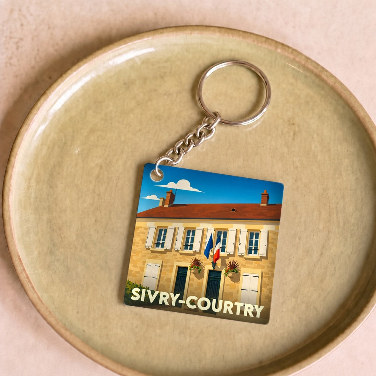 Porte-clés souvenir de la ville de Sivry-Courtry avec une illustration stylisée d'un bâtiment local.