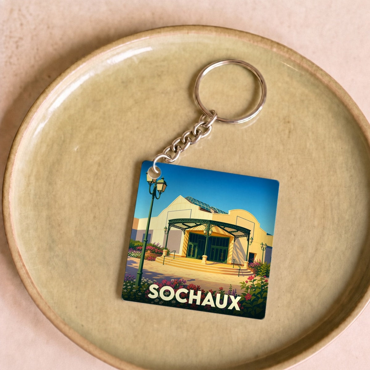 Porte-clés souvenir de la ville de Sochaux avec une illustration stylisée.
