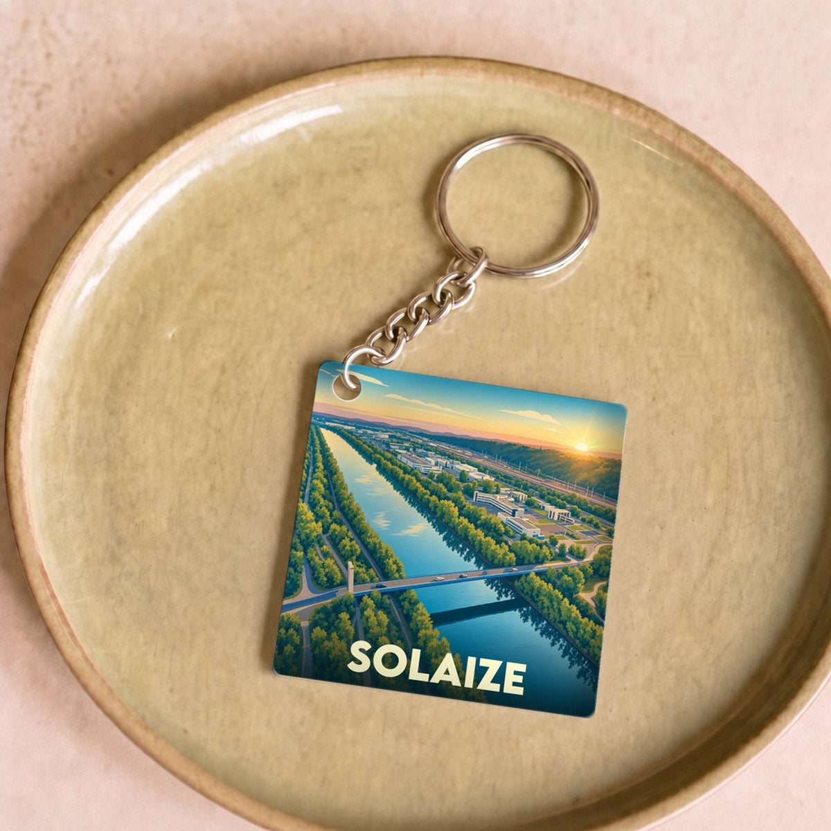 Porte-clés souvenir de la ville de Solaize avec une illustration stylisée d'un paysage fluvial au coucher du soleil.