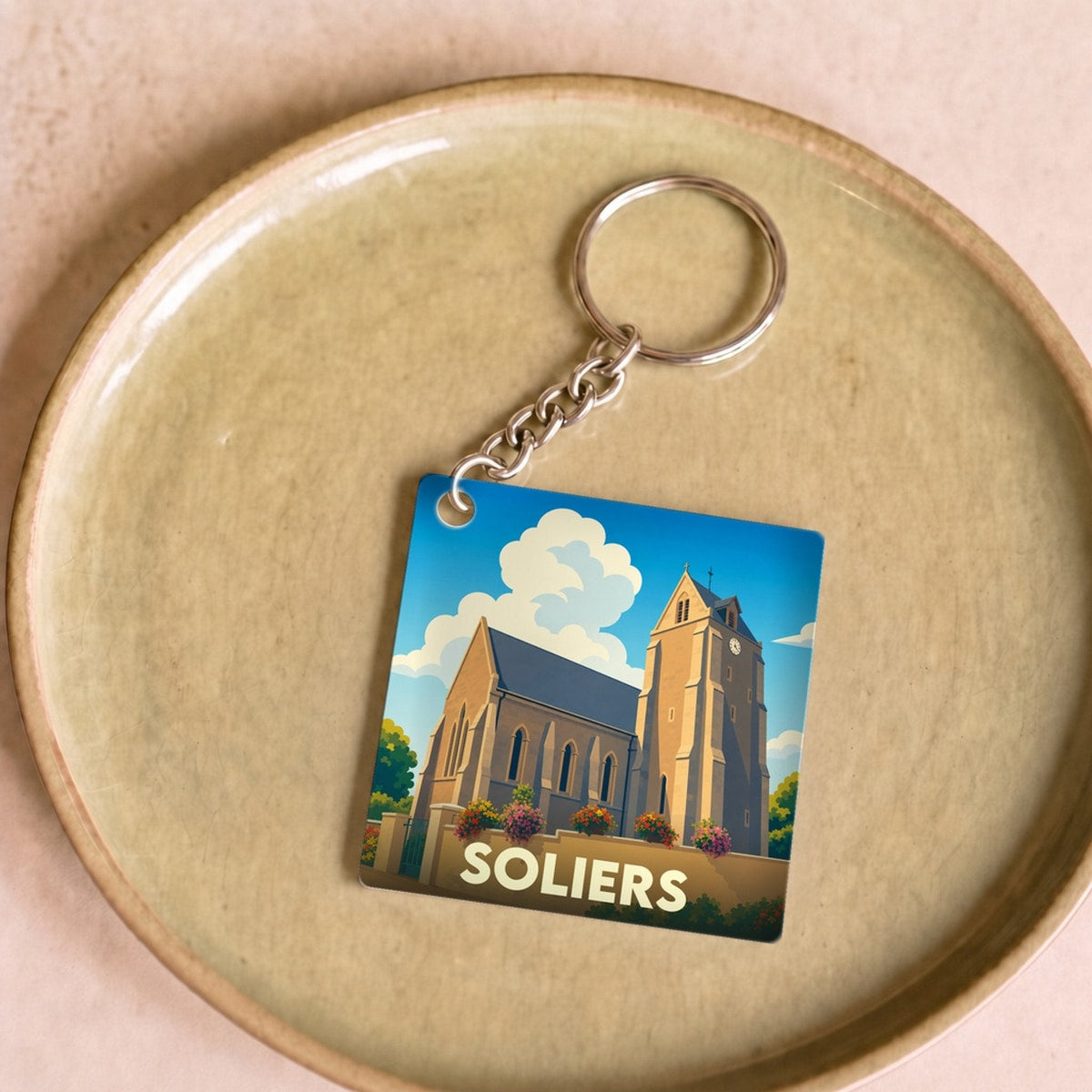 Porte-clés souvenir de la ville de Soliers avec une illustration stylisée de son église.