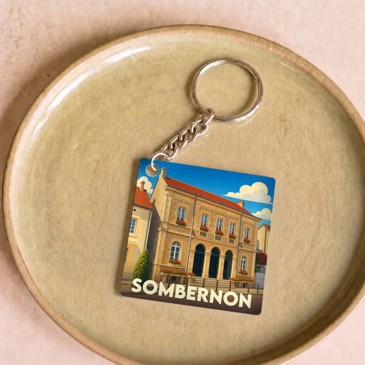 Porte-clés souvenir de la ville de Sombernon avec une illustration stylisée de son hôtel de ville.