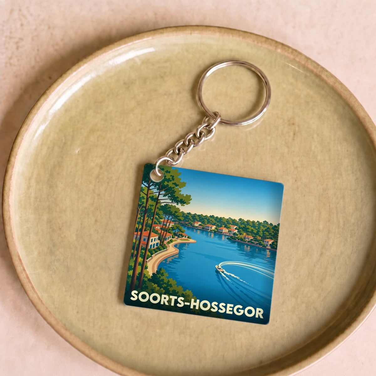 Porte-clés souvenir de la ville de Soorts-Hossegor avec une illustration stylisée du lac marin.