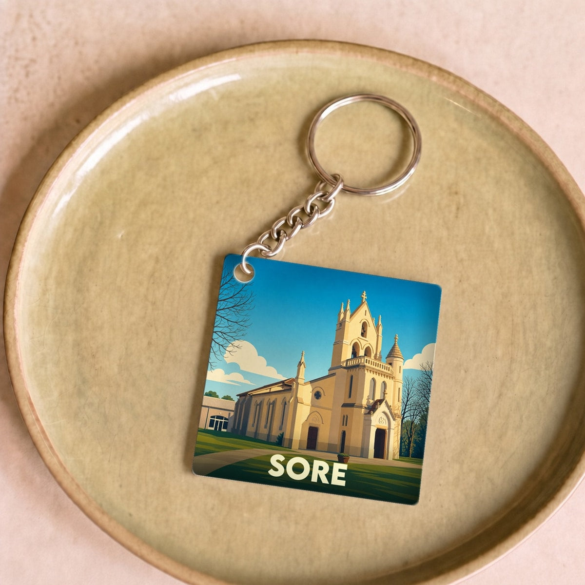 Porte-clés souvenir de la ville de Sore avec une illustration stylisée de son église.