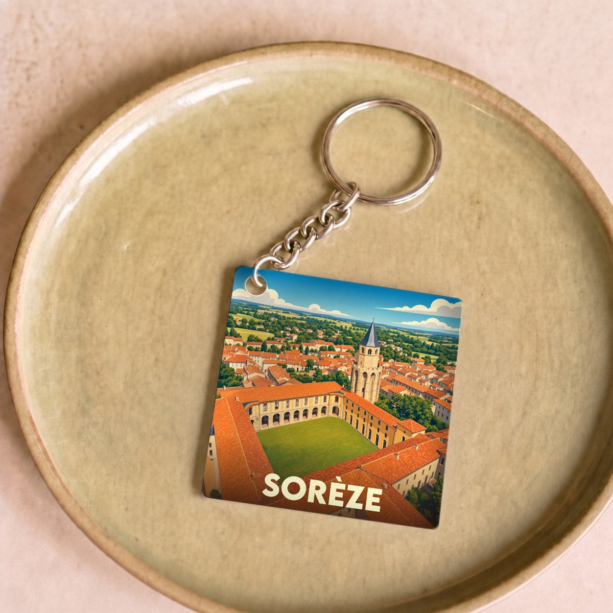 Porte-clés souvenir de la ville de Sorèze avec une illustration stylisée de son abbaye-école.