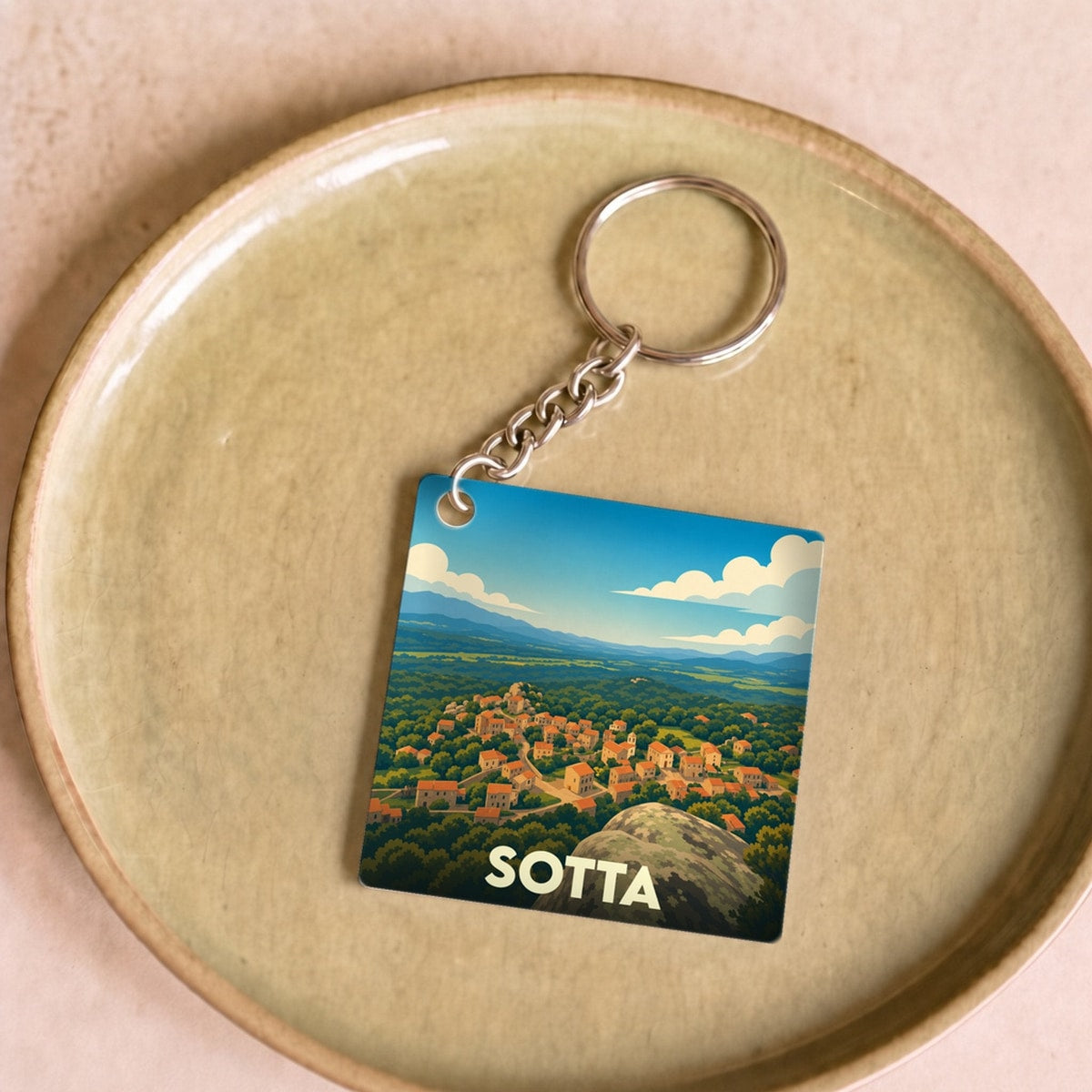 Porte-clés souvenir de la ville de Sotta avec une illustration stylisée d'un paysage corse.