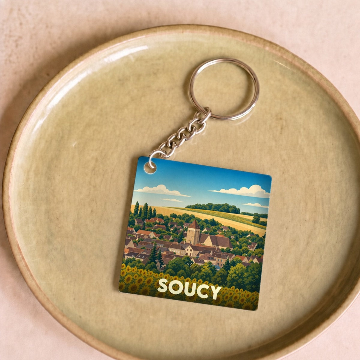 Porte-clés souvenir de la ville de Soucy avec une illustration stylisée de son paysage urbain et d'un champ de tournesols.