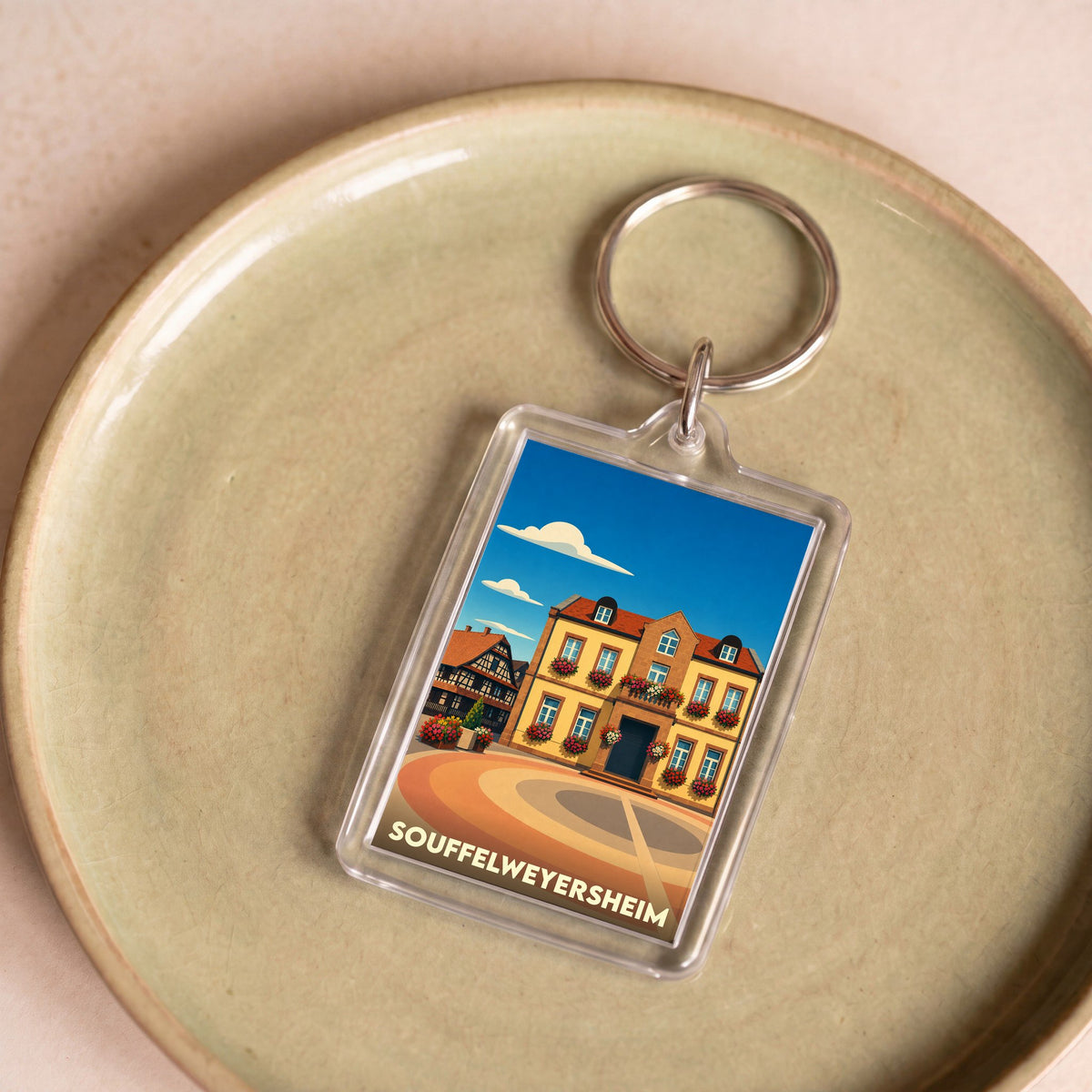 Porte-clés souvenir de la ville de Souffelweyersheim avec une illustration stylisée d'un bâtiment typique.