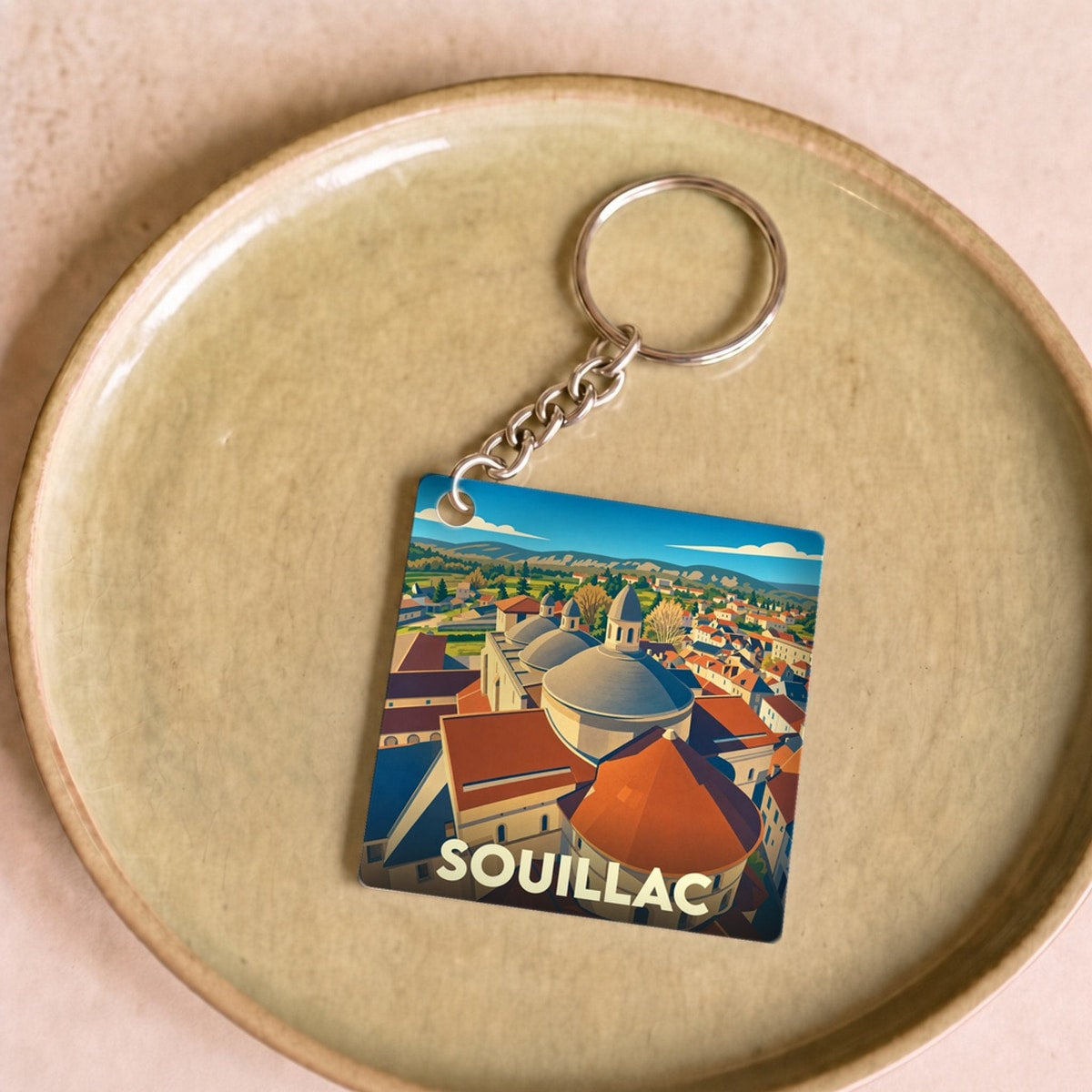 Porte-clés souvenir de la ville de Souillac avec une illustration stylisée de ses dômes.