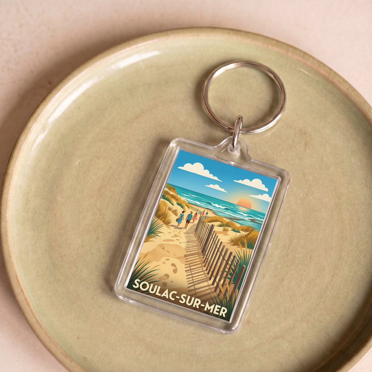 Porte-clés souvenir de la ville de Soulac-sur-Mer avec une illustration de plage stylisée.