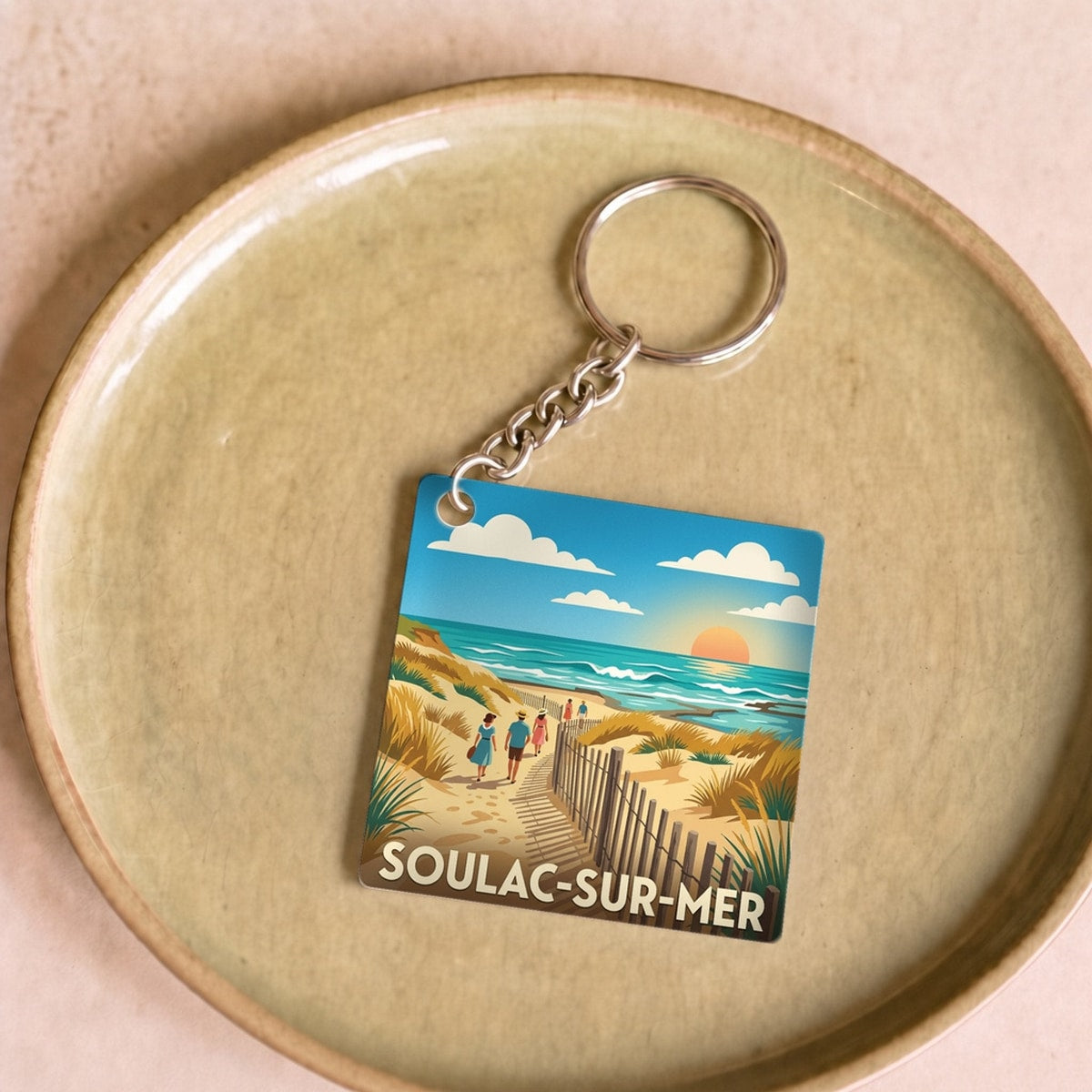 Porte-clés souvenir de la ville de Soulac-sur-Mer avec une illustration de plage stylisée.
