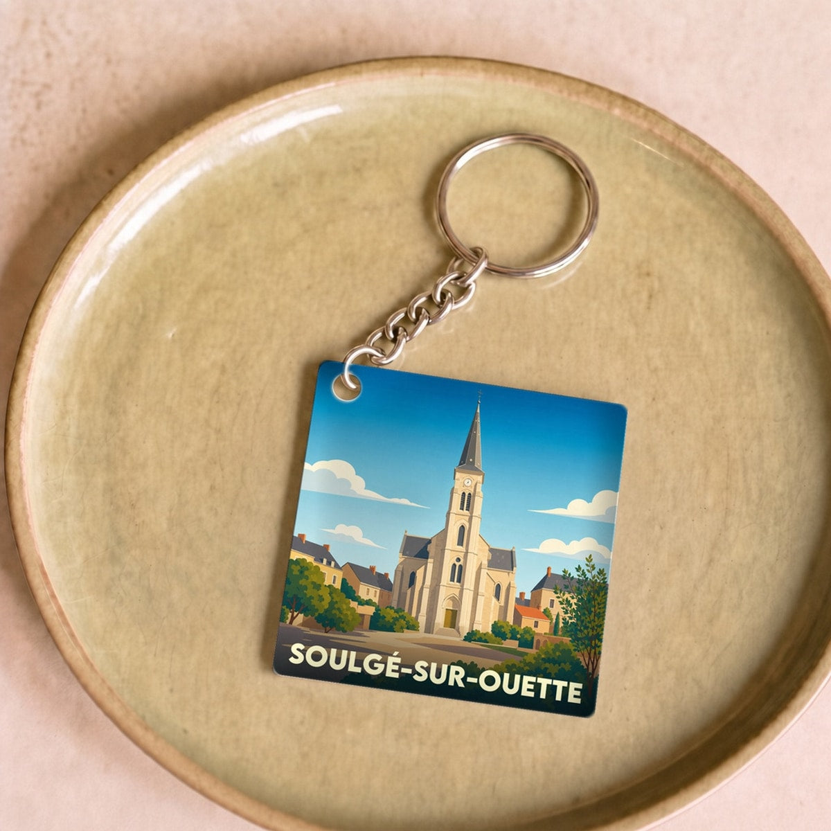 Porte-clés souvenir de la ville de Soulgé-sur-Ouette avec une illustration stylisée de son église.