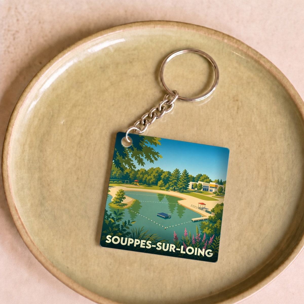 Porte-clés souvenir de la ville de Souppes-sur-Loing avec une illustration stylisée de sa base de loisirs.