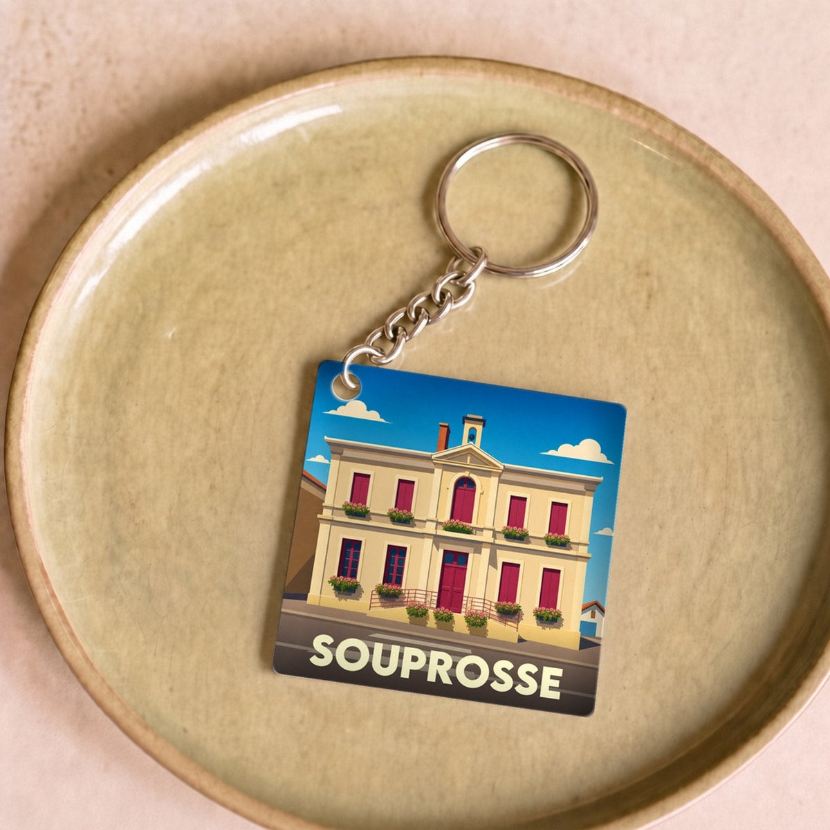 Porte-clés souvenir de la ville de Souprosse avec une illustration stylisée de sa mairie.