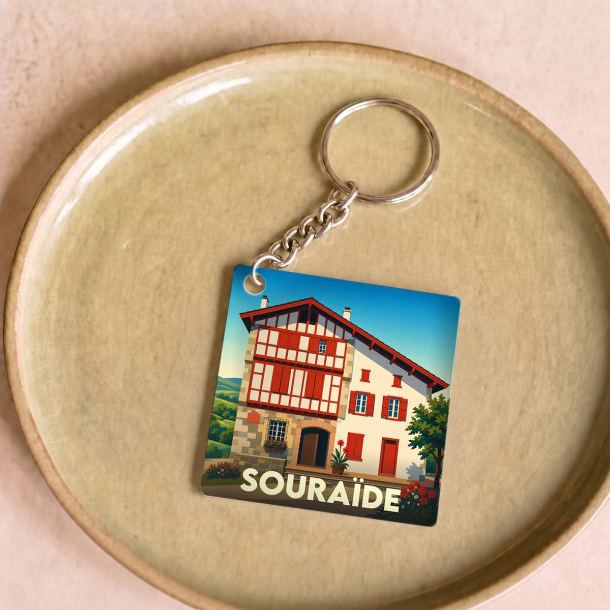 Porte-clés souvenir de la ville de Souraïde avec une illustration stylisée d'une maison basque traditionnelle.