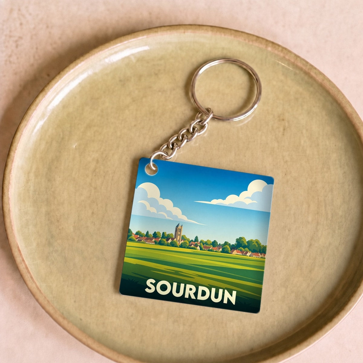 Porte-clés souvenir de la ville de Sourdun avec une illustration stylisée de son paysage.