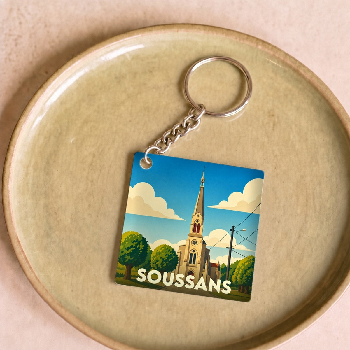 Porte-clés souvenir de la ville de Soussans avec une illustration stylisée de son église.