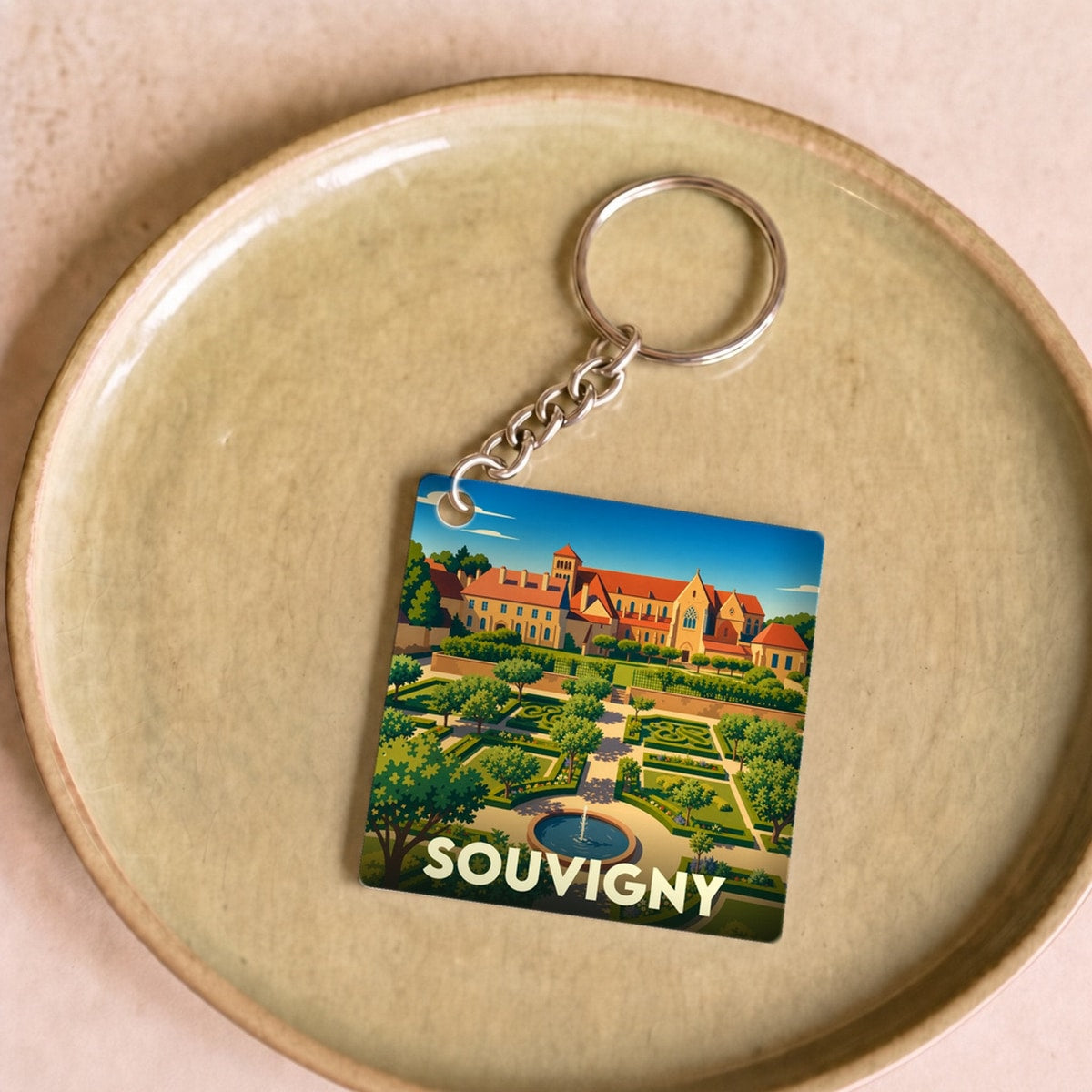 Porte-clés souvenir de la ville de Souvigny avec une illustration stylisée de son prieuré et de ses jardins.
