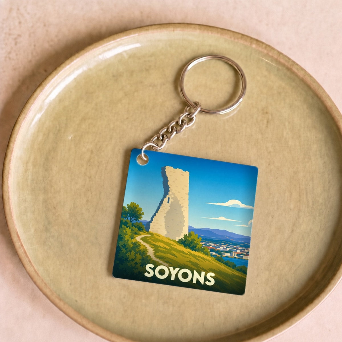 Porte-clés souvenir de la ville de Soyons illustrant sa tour médiévale dans un style épuré.