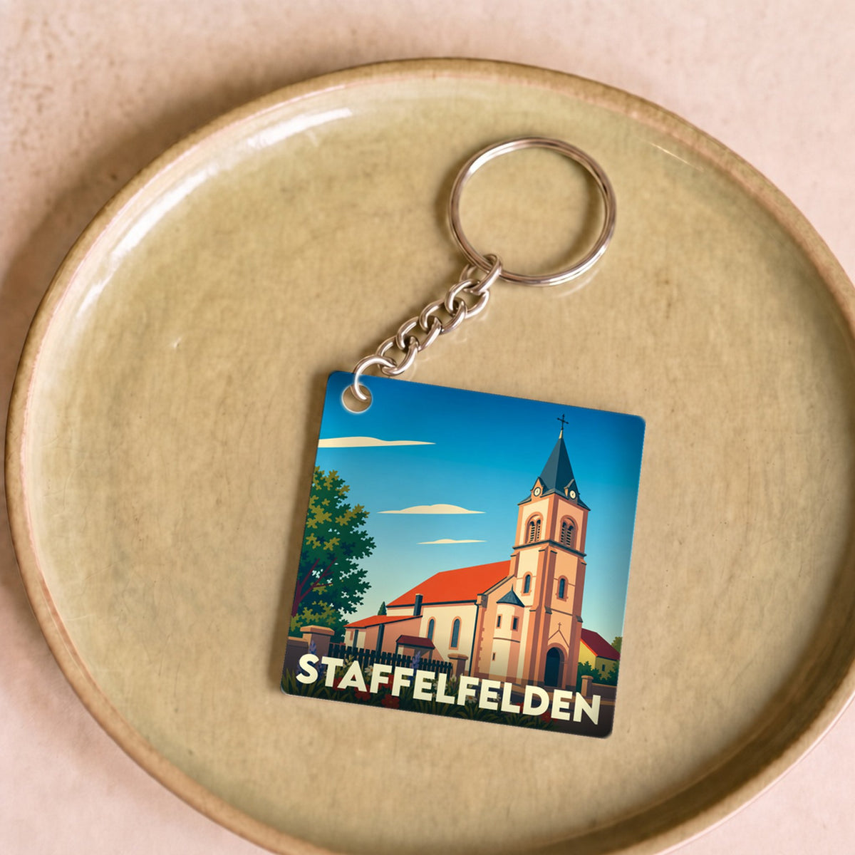 Porte-clés souvenir de la ville de Staffelfelden avec une illustration stylisée de son église.