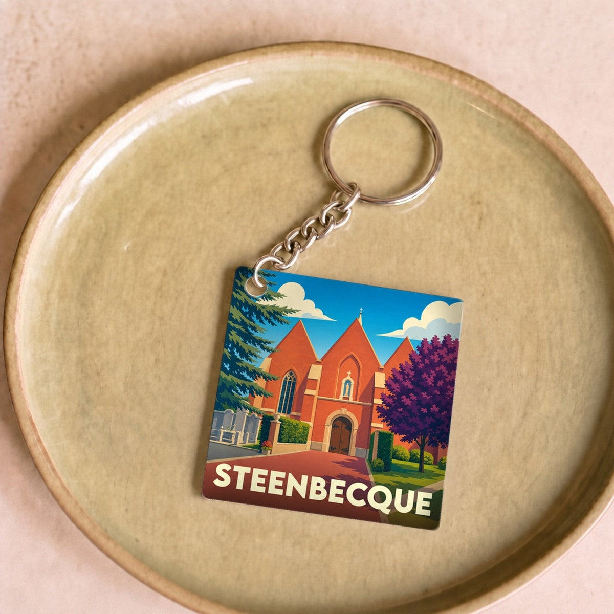 Porte-clés souvenir de la ville de Steenbecque avec une illustration stylisée de son église.