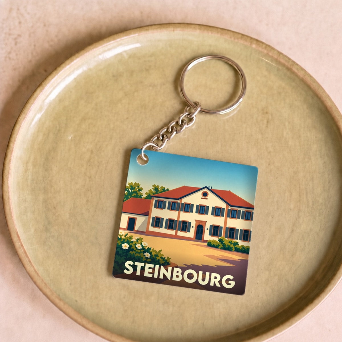 Porte-clés souvenir de la ville de Steinbourg avec une illustration stylisée d'un bâtiment traditionnel.
