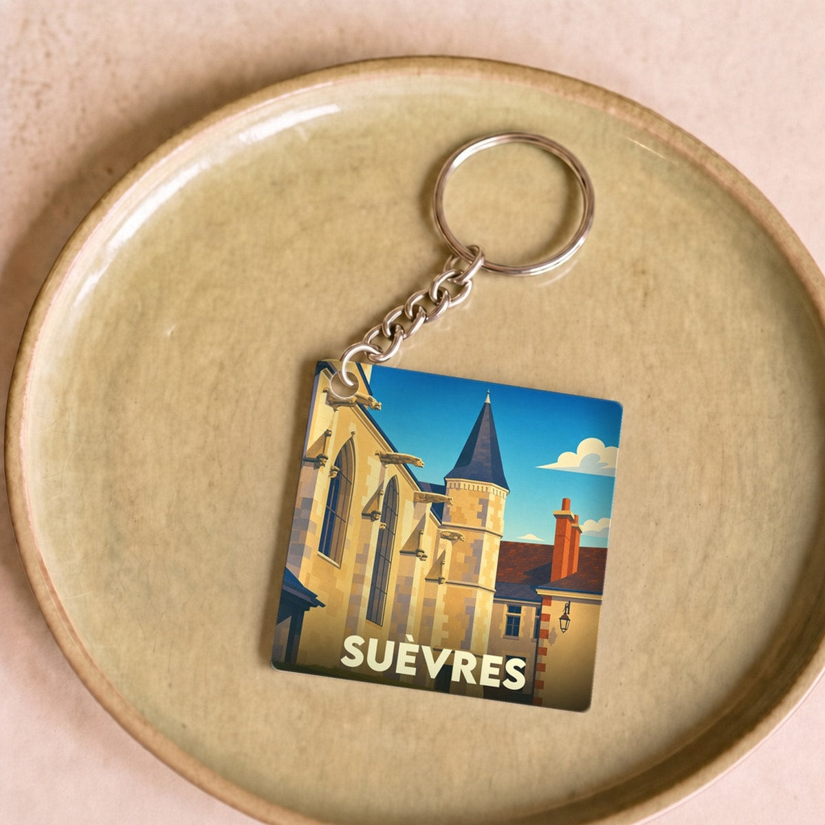 Porte-clés souvenir de la ville de Suèvres avec une illustration stylisée de son patrimoine architectural.