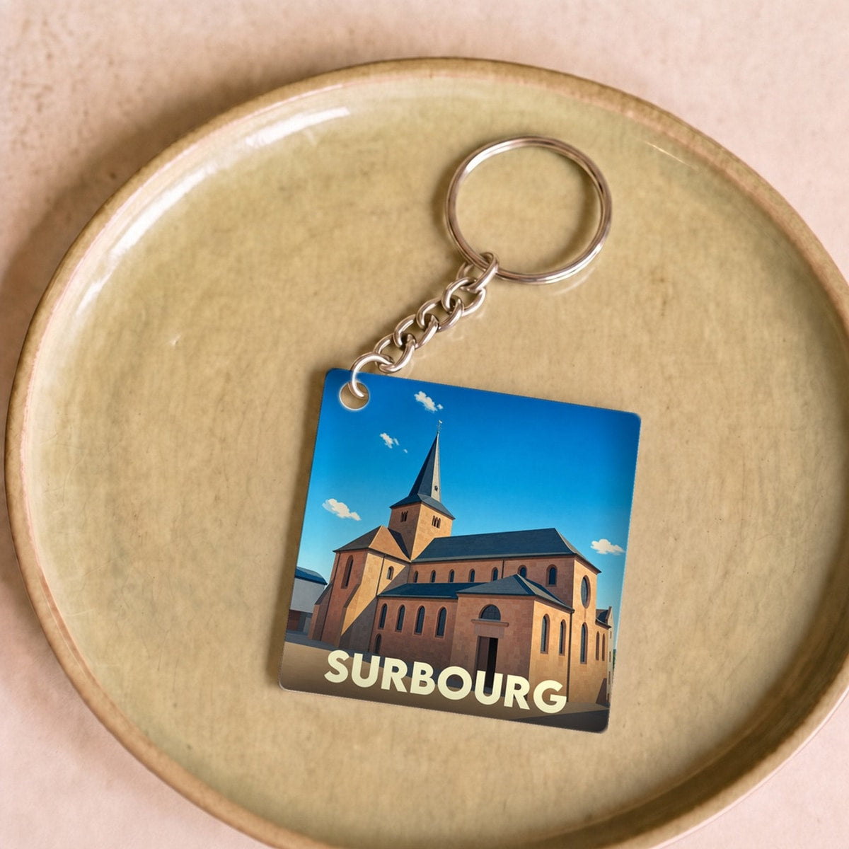 Porte-clés souvenir de la ville de Surbourg avec une illustration stylisée de son église.