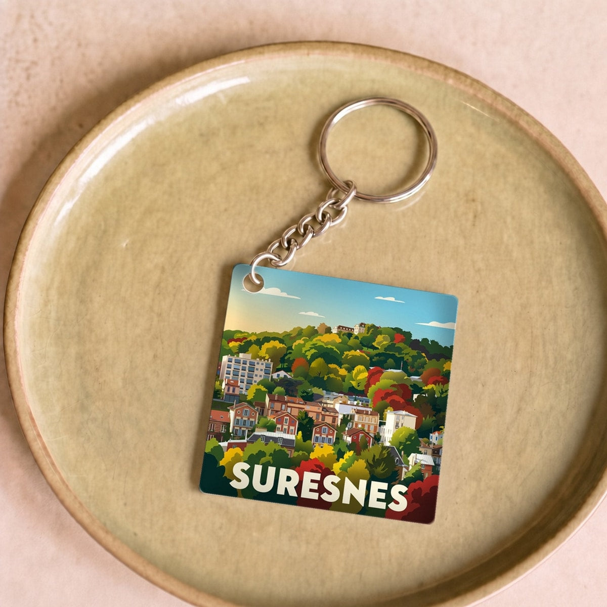 Porte-clés souvenir de la ville de Suresnes arborant une illustration stylisée et colorée.