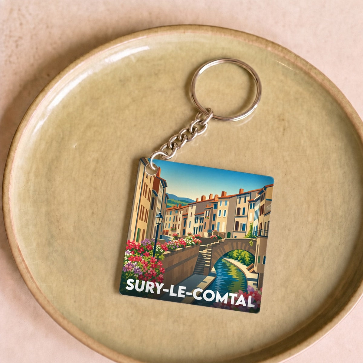 Porte-clés souvenir de la ville de Sury-le-Comtal avec une illustration stylisée.