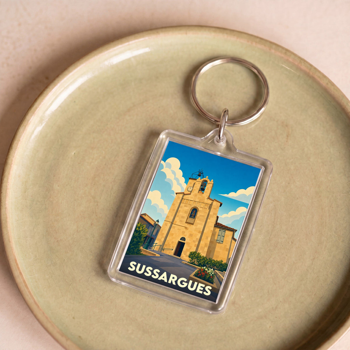 Porte-clés souvenir de la ville de Sussargues avec une illustration stylisée de son église.