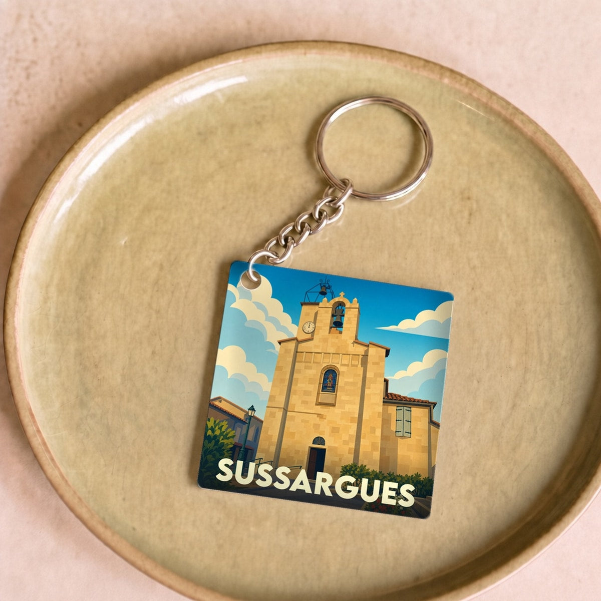 Porte-clés souvenir de la ville de Sussargues avec une illustration stylisée de son église.