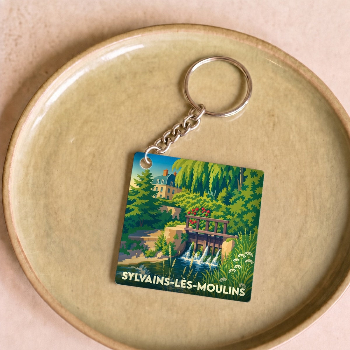 Porte-clés souvenir de la ville de Sylvains-Lès-Moulins avec une illustration stylisée d'un moulin et sa rivière.