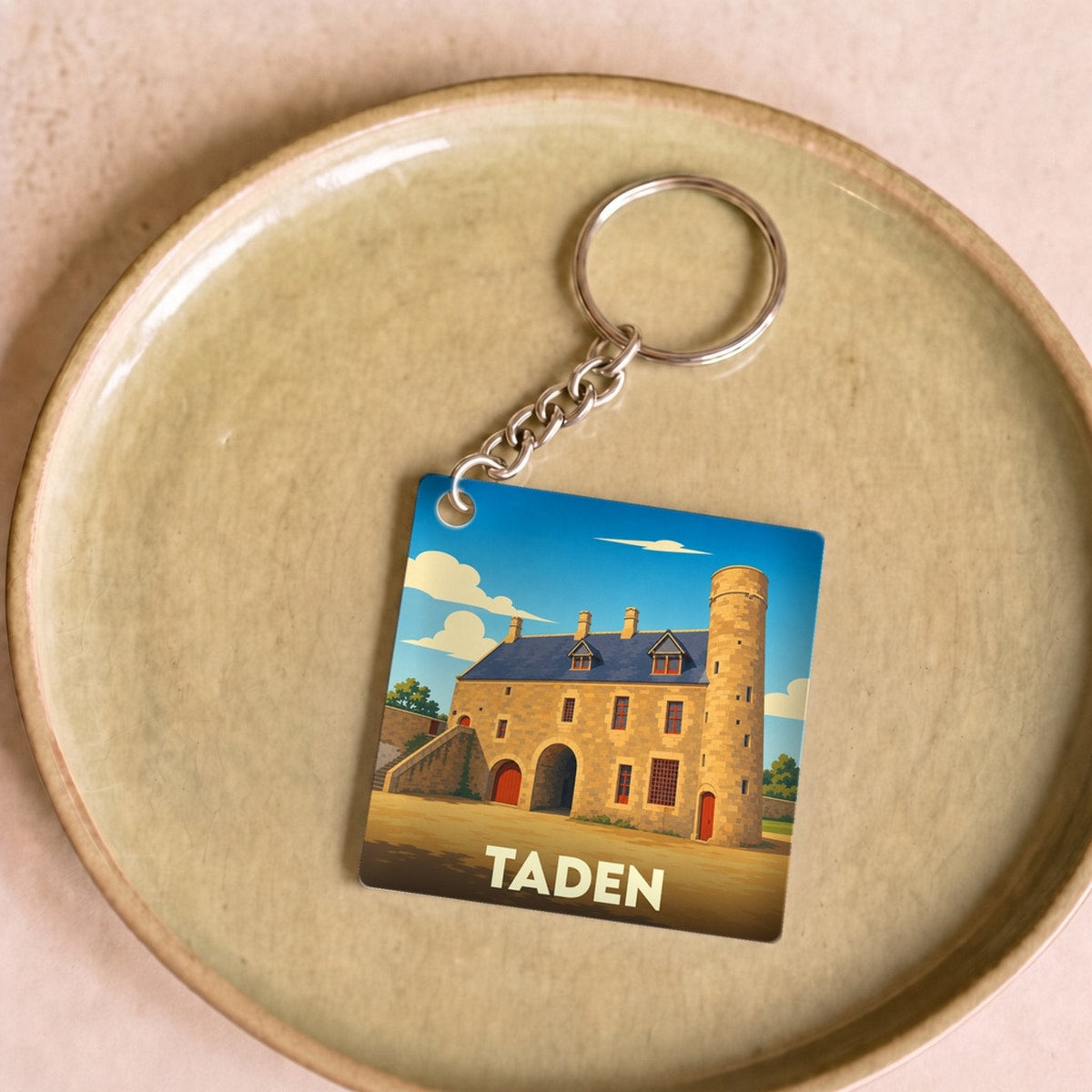 Porte-clés souvenir de la ville de Taden avec une illustration stylisée d'un manoir médiéval.