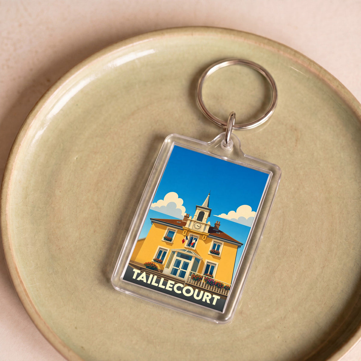 Porte-clés souvenir de la ville de Taillecourt avec une illustration stylisée de sa mairie.