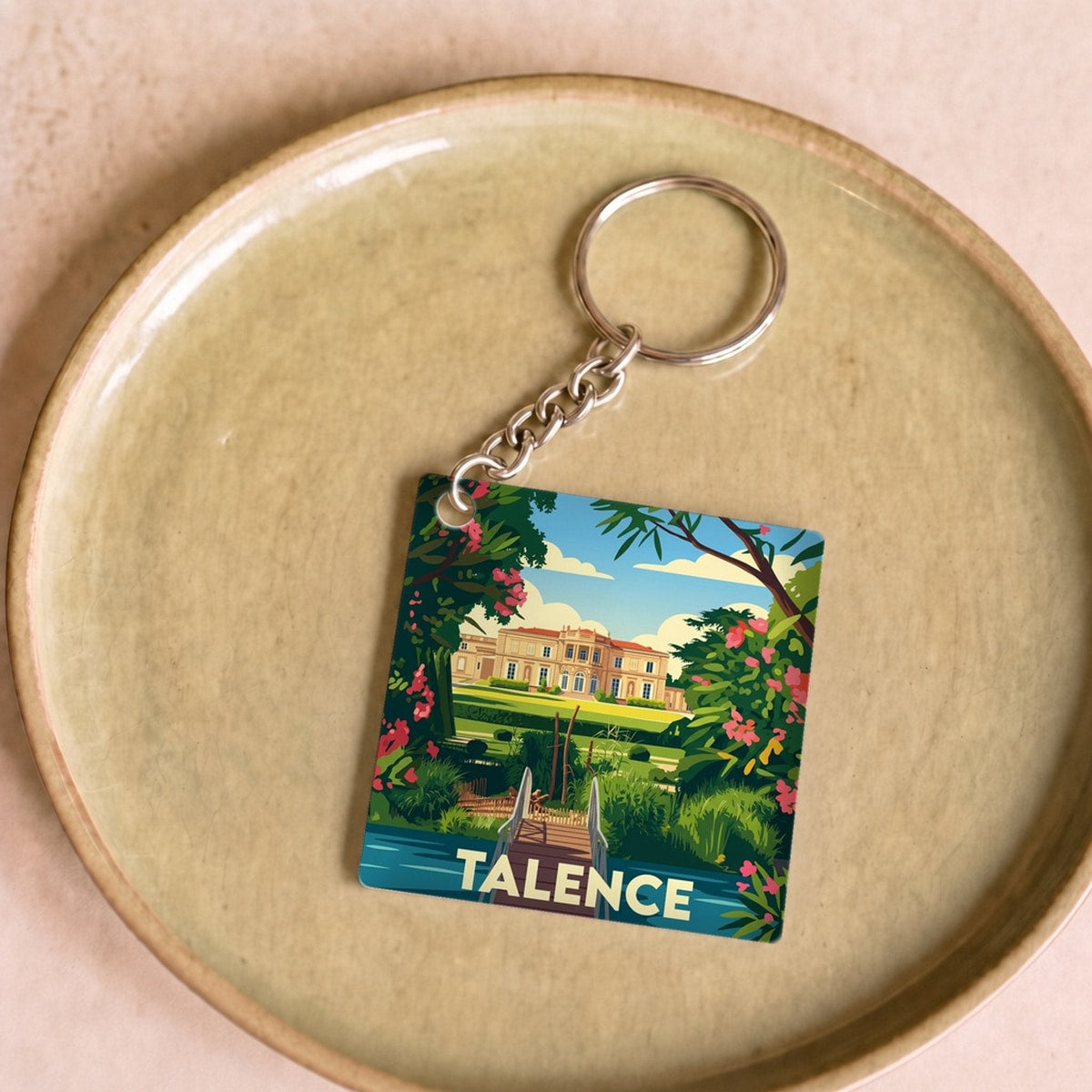 Porte-clés souvenir de la ville de Talence avec une illustration stylisée d'un paysage verdoyant.