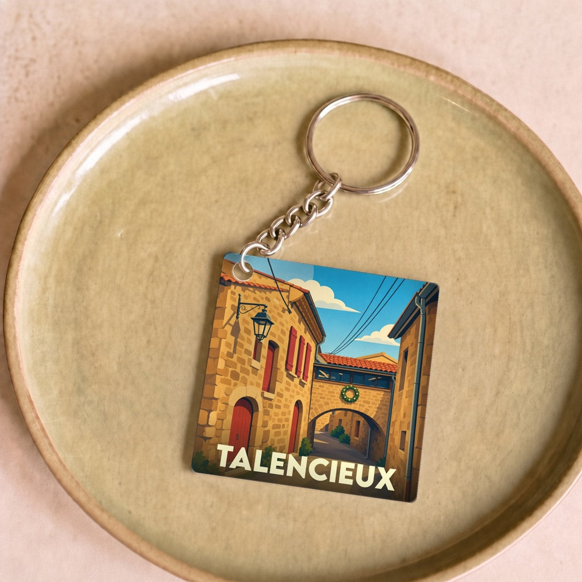 Porte-clés souvenir de la ville de Talencieux avec une illustration stylisée d'une ruelle ensoleillée.