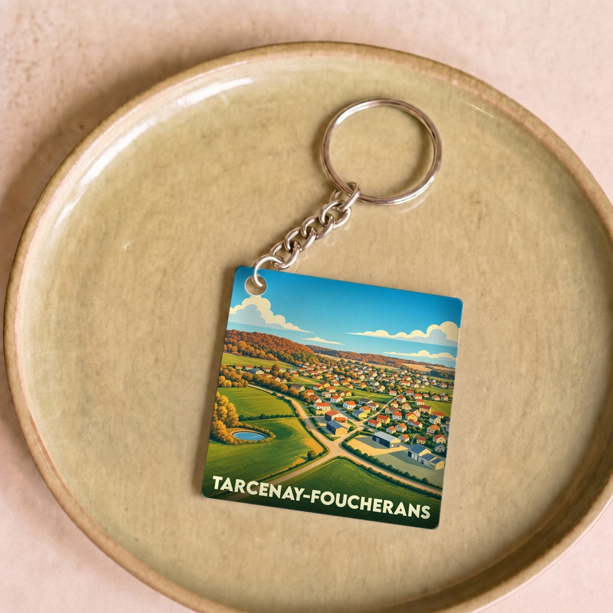 Porte-clés souvenir de la commune de Tarcenay-Foucherans avec une illustration stylisée du village vu du ciel.