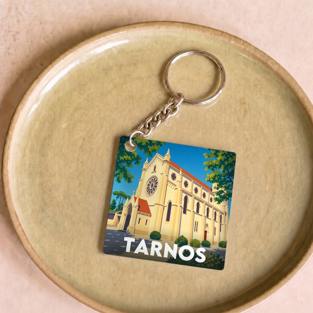 Porte-clés souvenir de la ville de Tarnos avec une illustration stylisée d'une église.