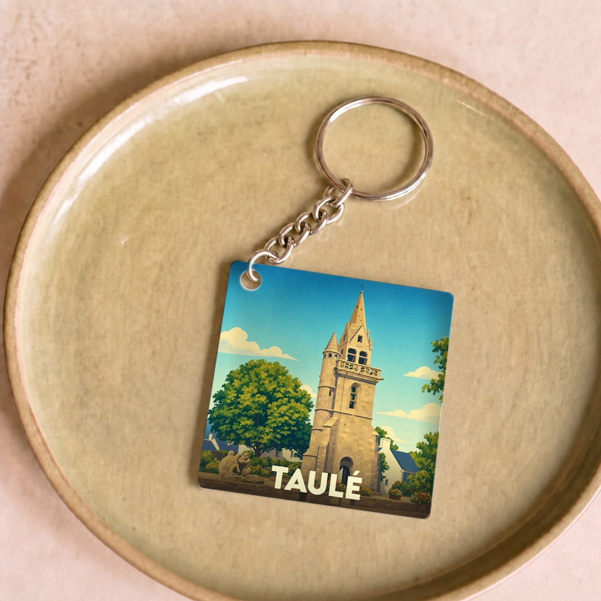 Porte-clés souvenir de la ville de Taulé avec une illustration stylisée de son clocher.