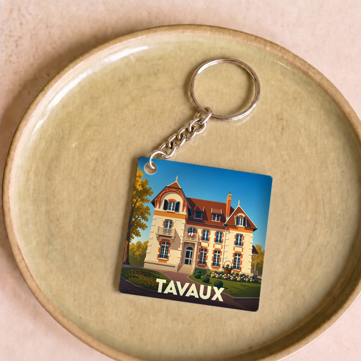 Porte-clés souvenir de la ville de Tavaux avec une illustration stylisée d'une grande demeure bourgeoise.