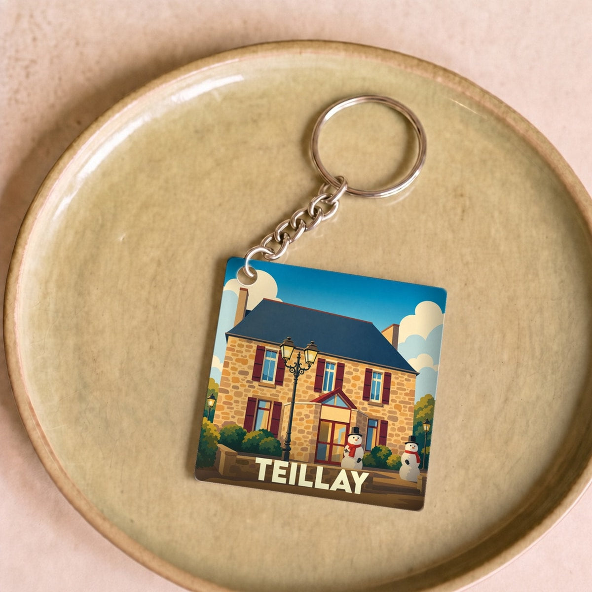 Porte-clés souvenir de la ville de Teillay avec une illustration stylisée d'un bâtiment en pierre.