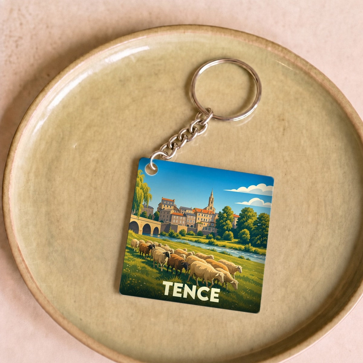 Porte-clés souvenir de la ville de Tence avec une illustration stylisée d'un paysage pastoral.