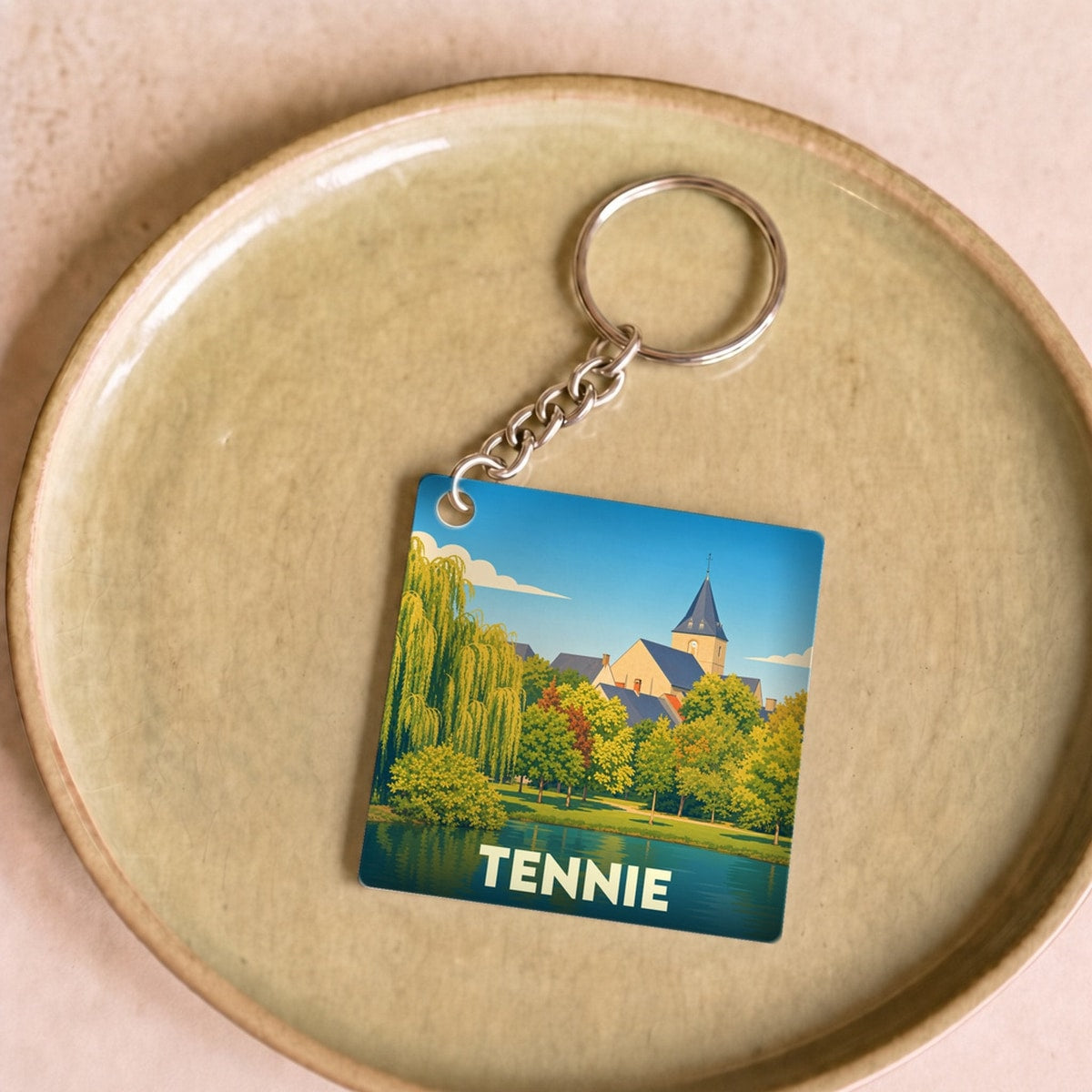 Porte-clés souvenir de la ville de Tennie avec une illustration stylisée d'un paysage lacustre.