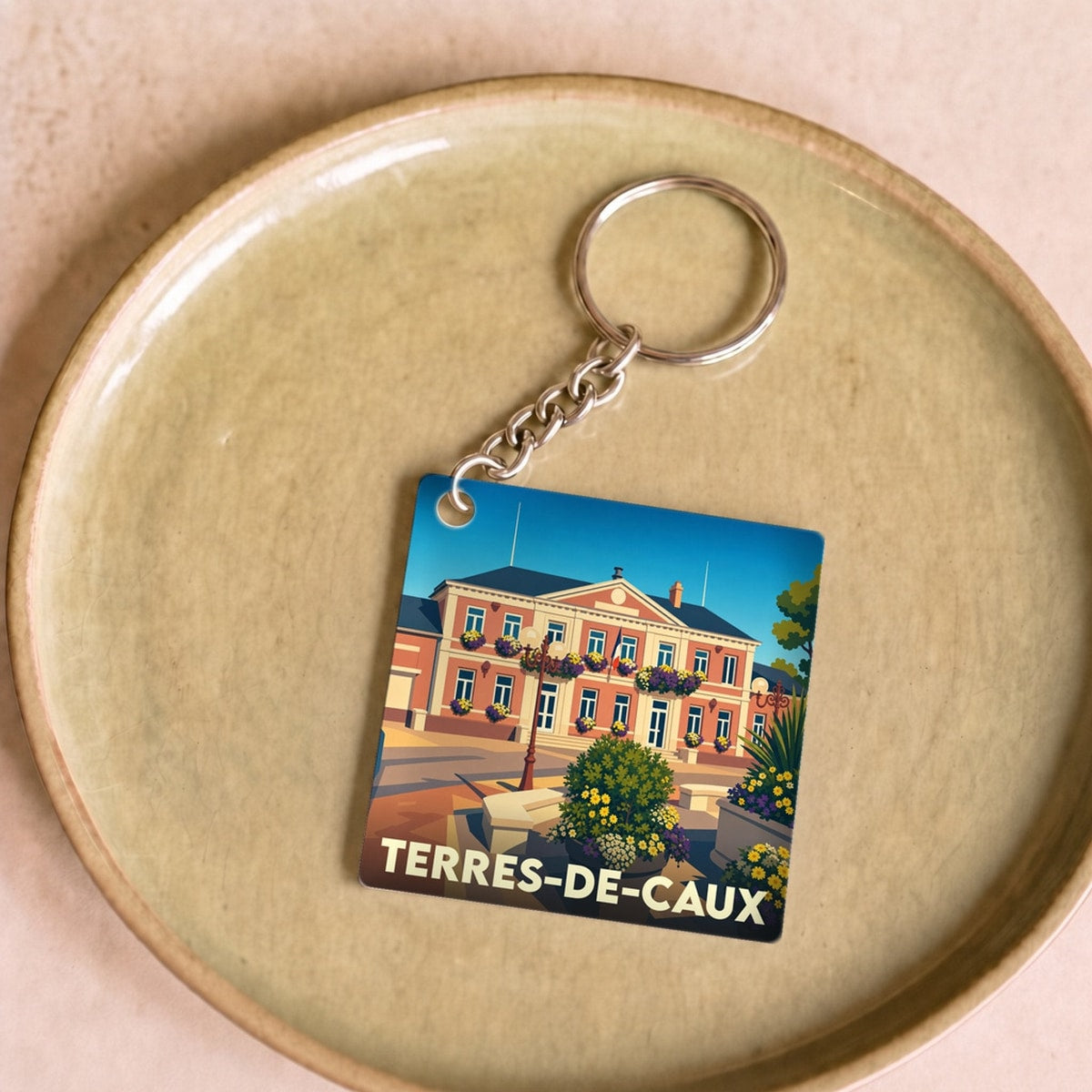 Porte-clés souvenir de la ville de Terres-de-Caux avec une illustration stylisée de la mairie.