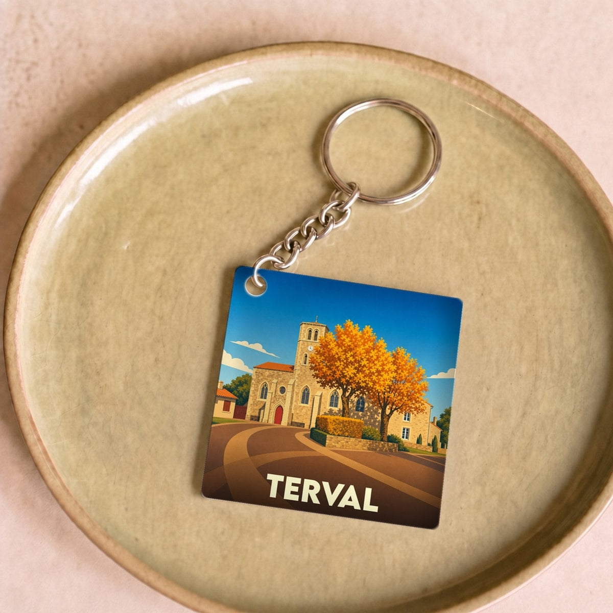 Porte-clés souvenir de la ville de Terval avec une illustration stylisée d'une église et d'un arbre d'automne.