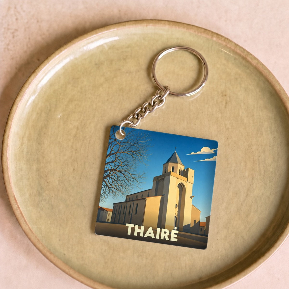 Porte-clés souvenir de la ville de Thairé avec une illustration stylisée de son église.